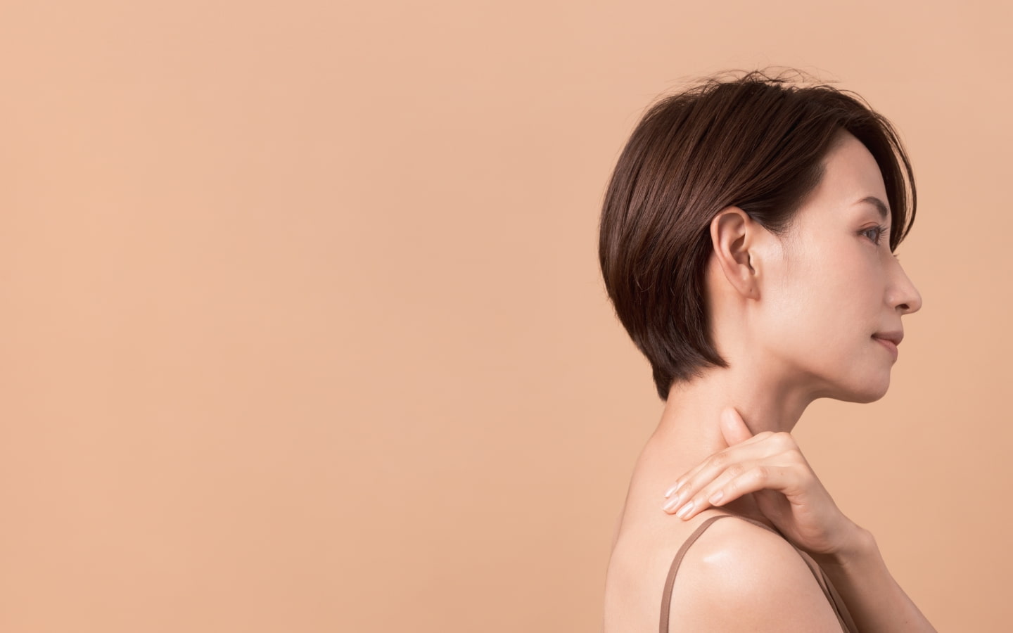 肩に手を添え、美しい肌の質感が際立つ横顔の女性のメインビジュアル